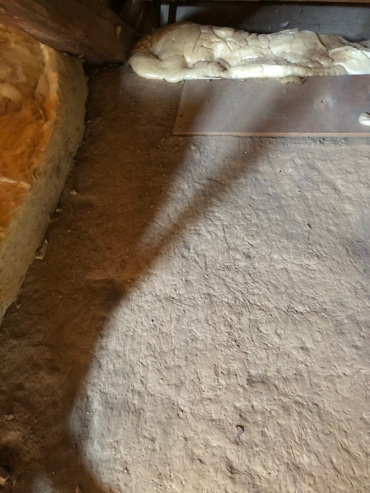 Rohbaukellerboden mit unebenem Erdboden, Holzbalken und Dämmmaterial
