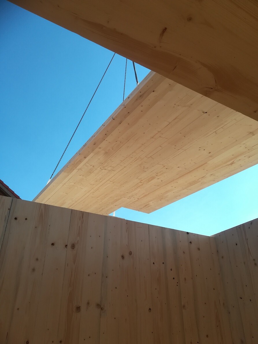 Timber frame construction at a building site with beams and blue sky