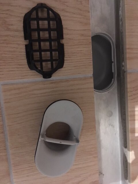 Bathroom floor with floor drain, siphon, and tiles during construction