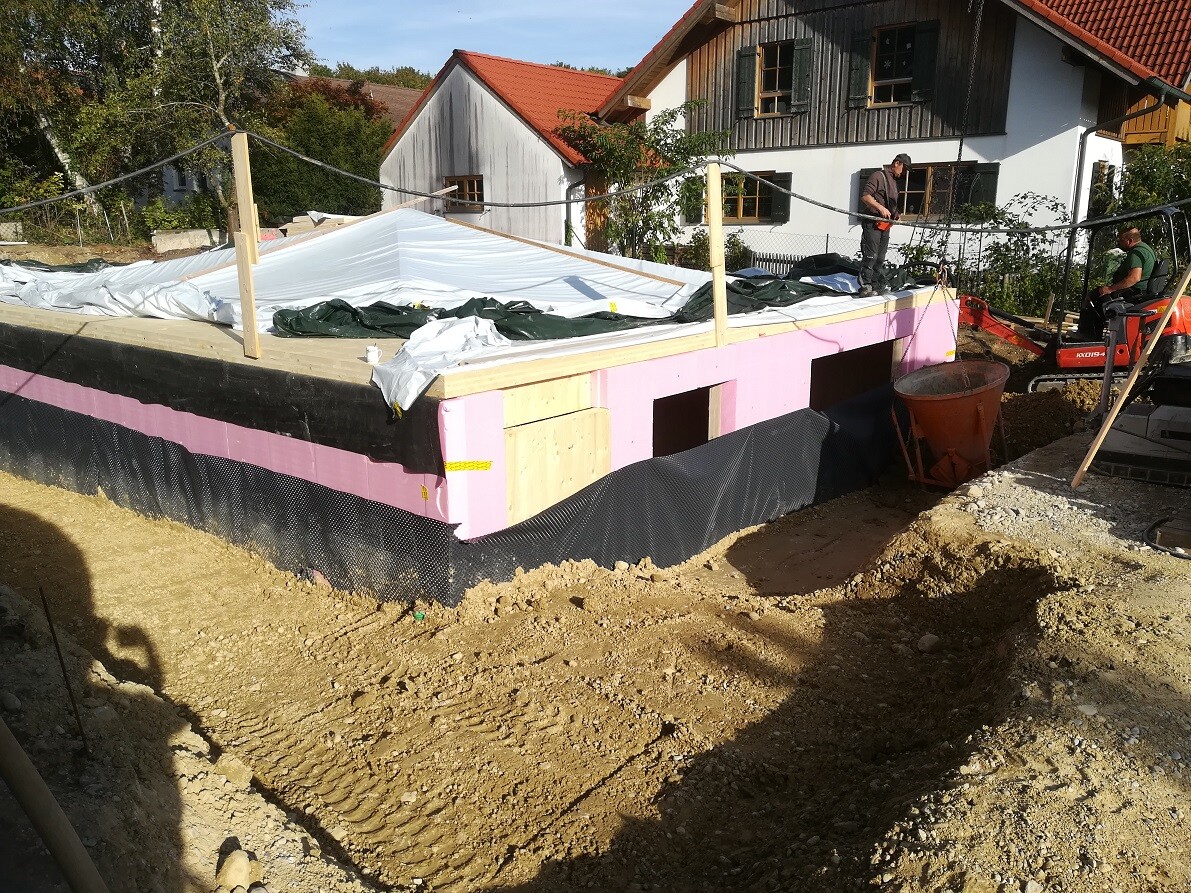 Construction site with shell foundation, pink insulation and construction workers on site