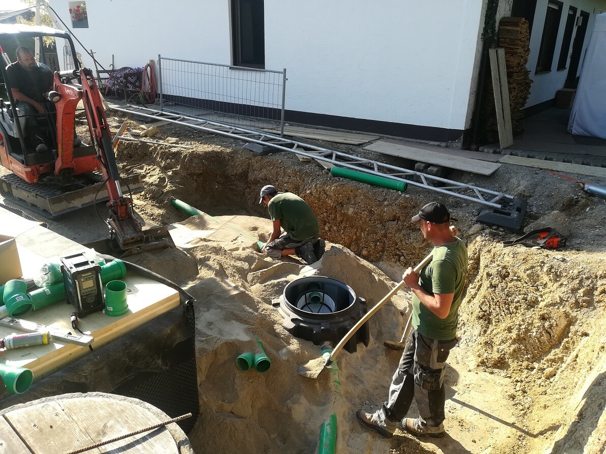 Construction workers working in an excavation; the structural foundation and piping are being installed.