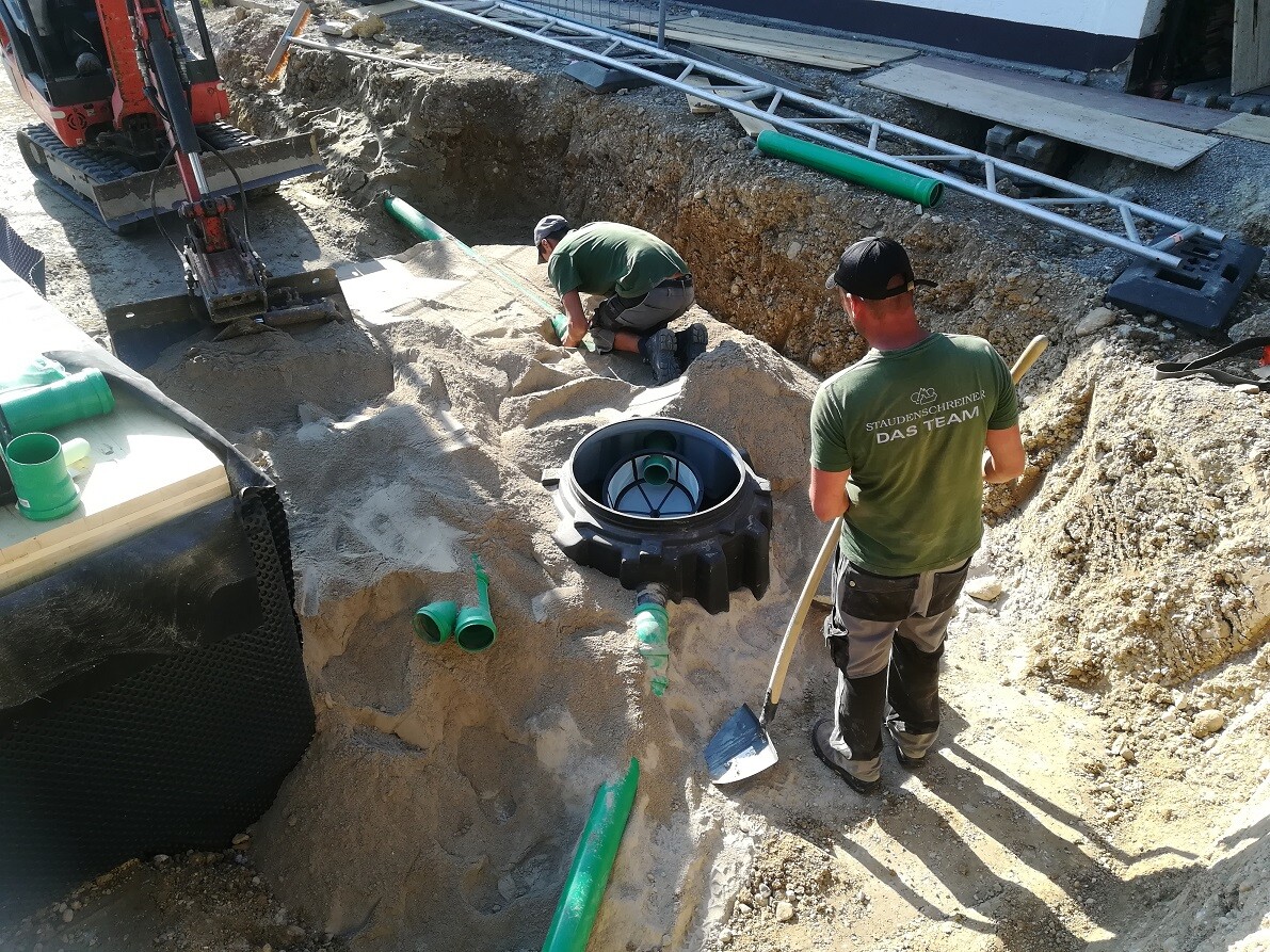 Two construction workers working in an excavation with pipes and shovels