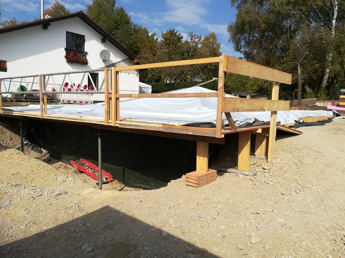 Building plot with temporary wooden terrace and foundation work in front of a house