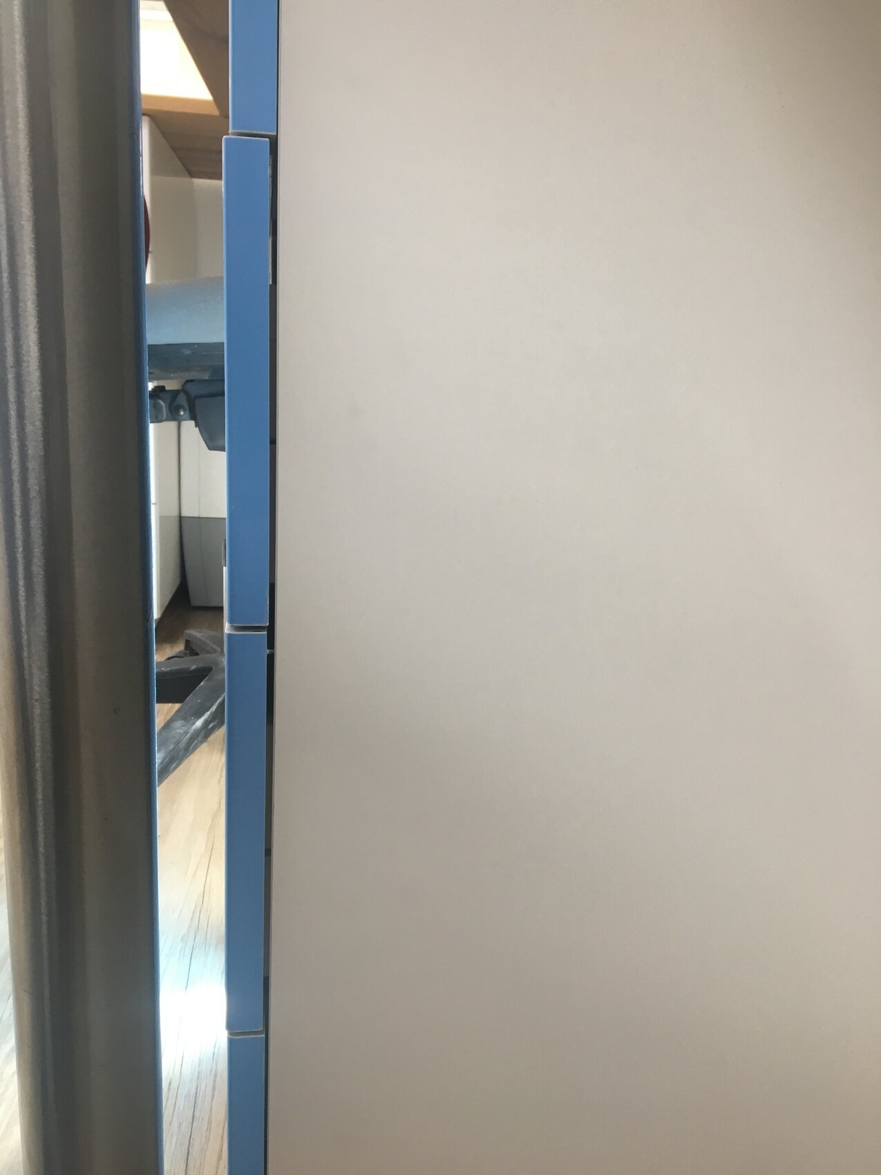 Close-up of a blue cabinet door with visible hinges and gray interior wall
