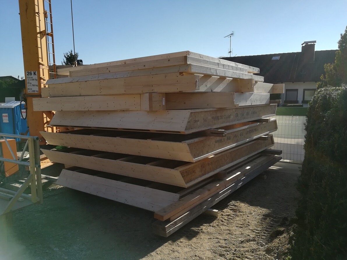Stack of raw wooden beams and construction timber on the construction site next to the house