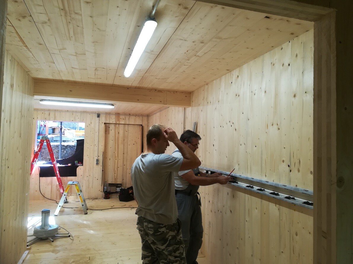 Two construction workers checking wood paneling during interior finishing work with measuring tools