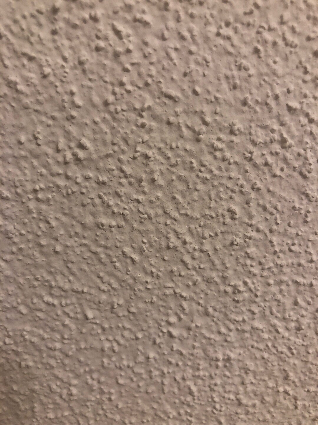 Close-up of a roughly textured beige plaster wall surface