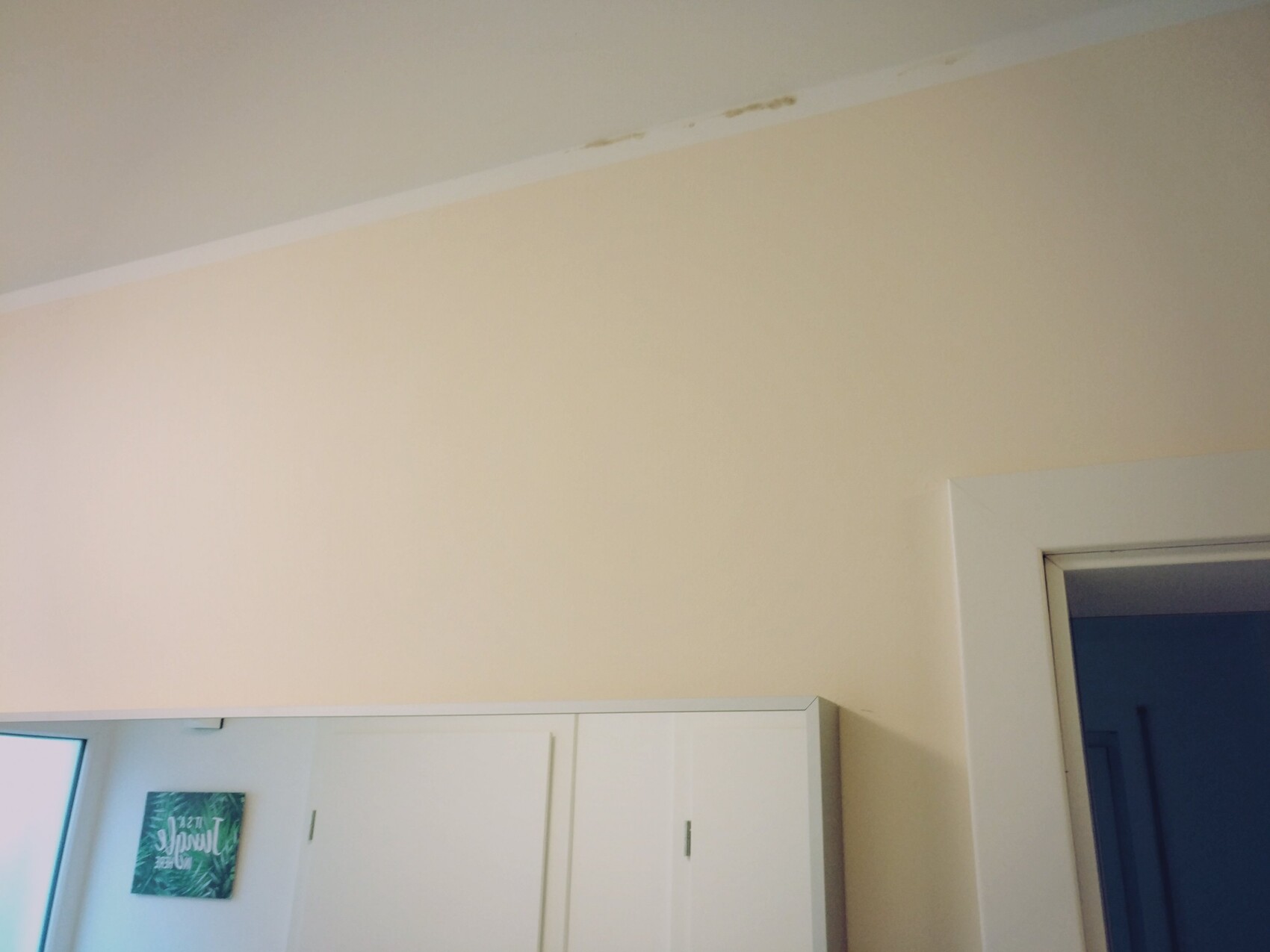 Beige Wand mit weißen Küchenschränken und Türrahmen