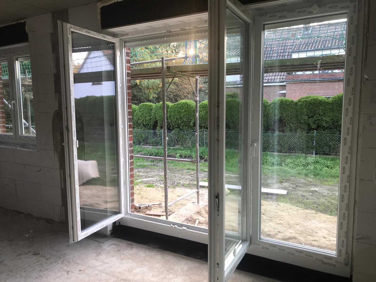 Grosse Glasschiebeturen im unfertigen Innenraum öffnen zum Garten.
