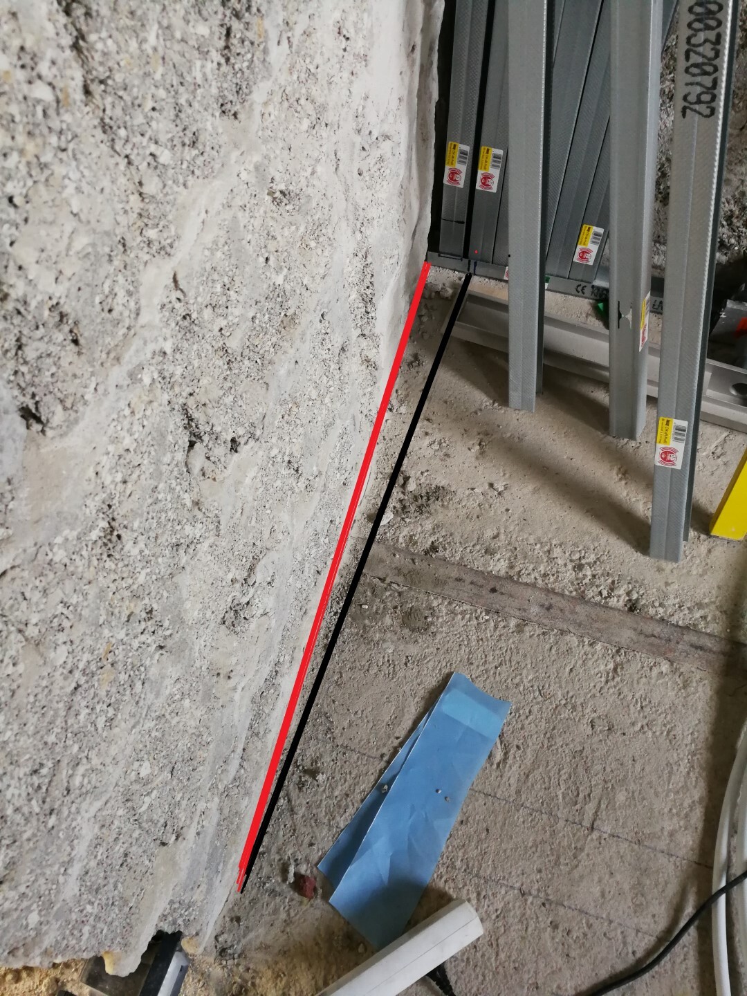 Indoor construction site with metal stud walls, raw concrete floor, and cables