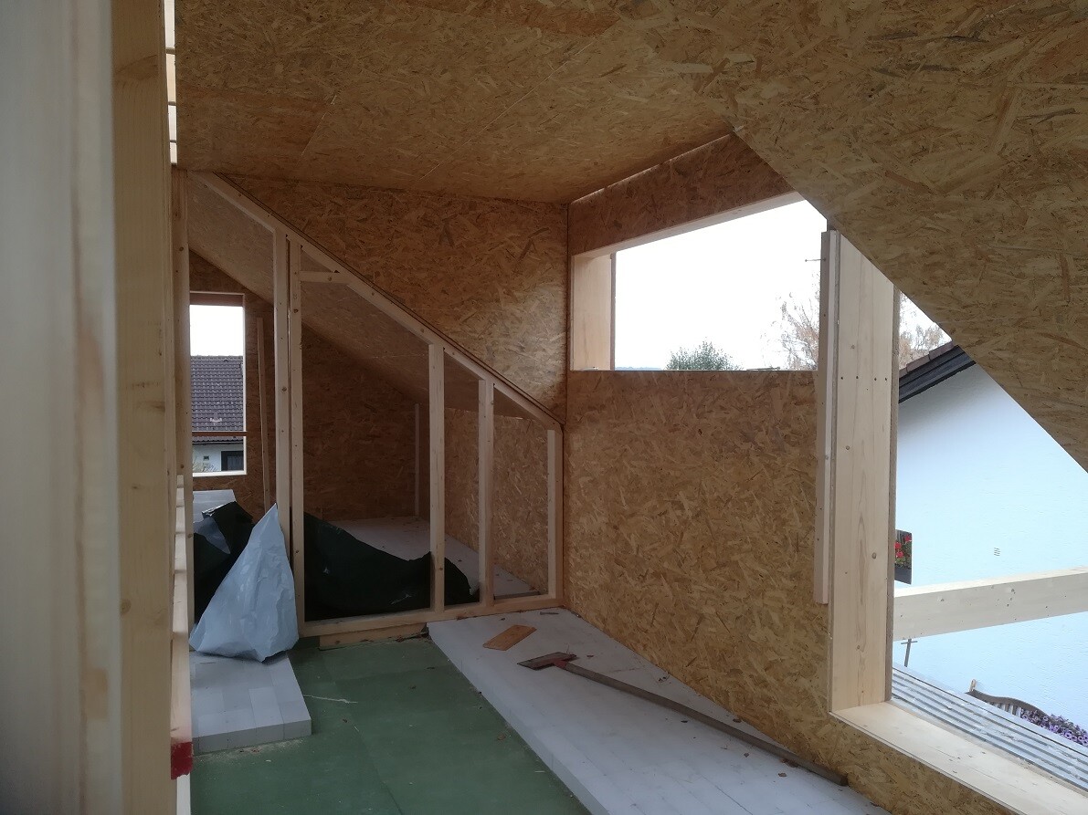 Shell interior of an attic with OSB boards, wooden frame, and window opening