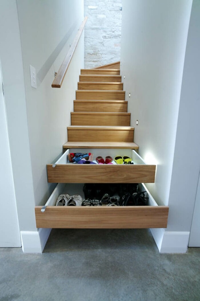 Wooden stairs with two pull-out drawers underneath, filled with shoes.