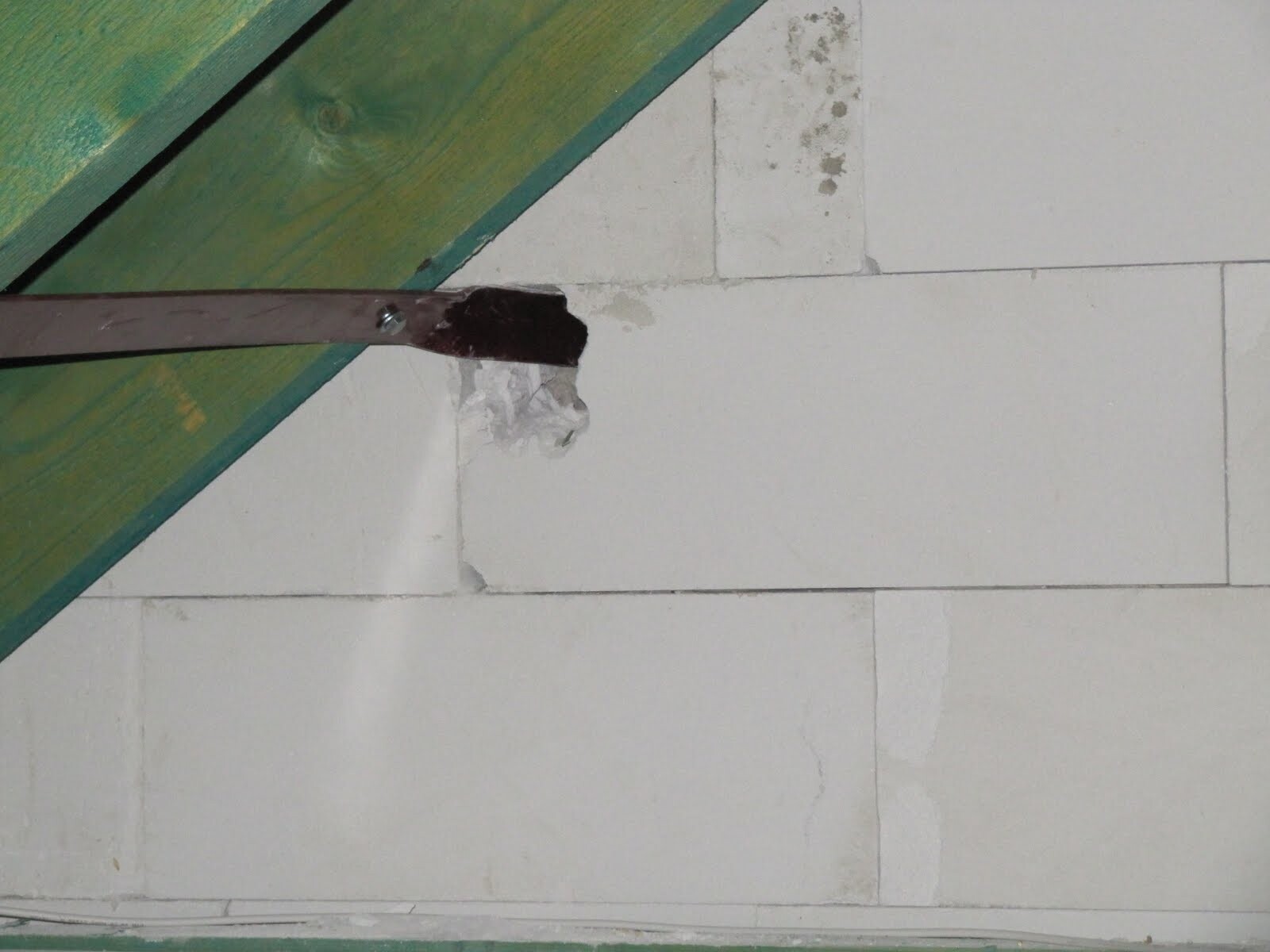 Unplastered shell with green wooden beam and damaged wall