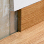 Close-up of a metal door threshold between wooden floor, focus on floor edge