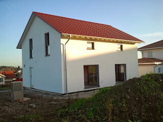 Two-story white house with red tiled roof and building plot