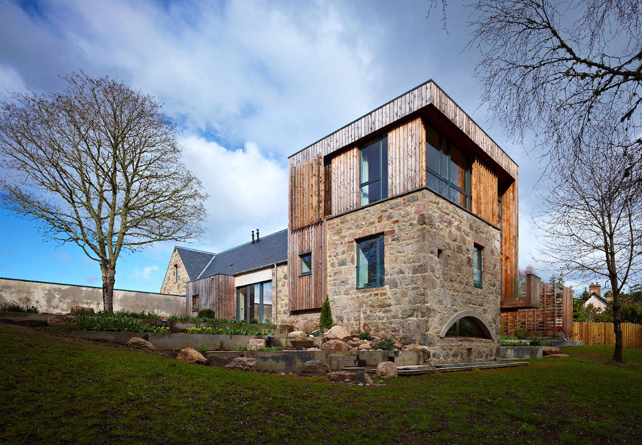 Exterior view of a modern house with stone base, wooden cladding, and garden