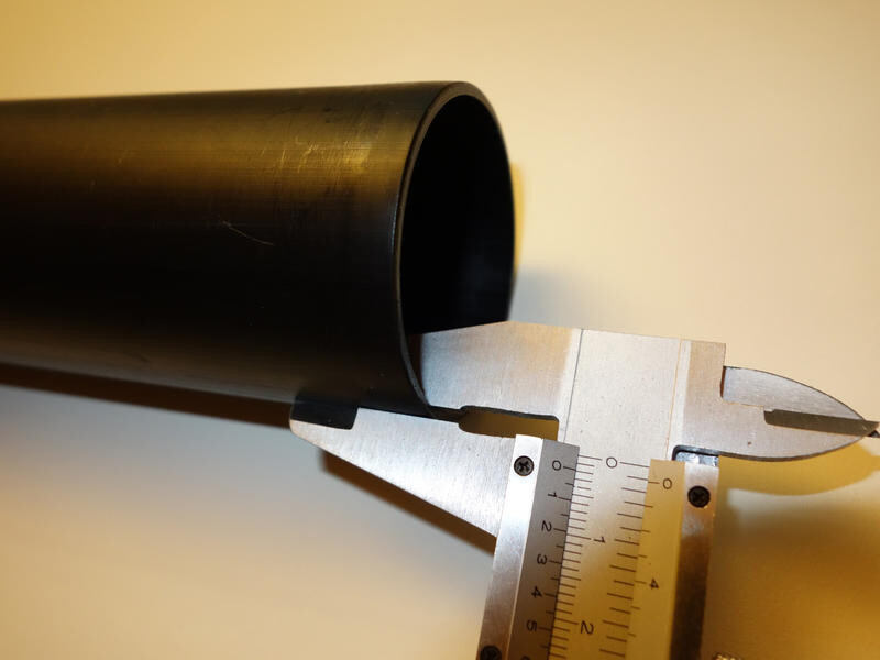 Black pipe section being measured with calipers; focus on building services measurement.