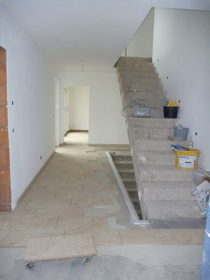 Bright hallway in interior finishing with unfinished staircase and construction tools on site