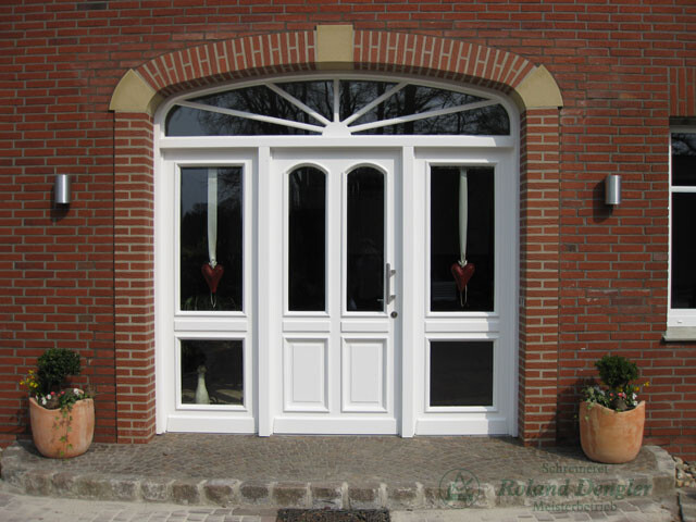 White double door with arched window above, brick wall, planter, heart decoration in windows.