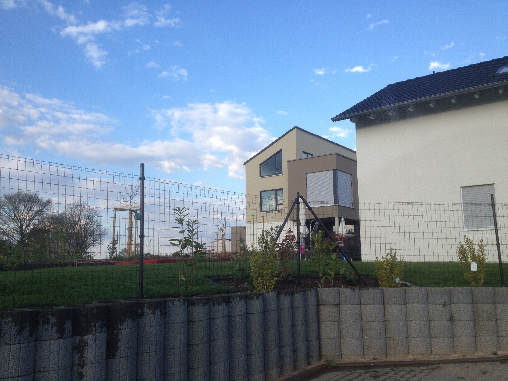 Exterior view of a modern single-family house with garden and fence