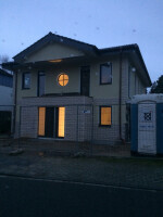 Modern brick house front at dusk with illuminated windows