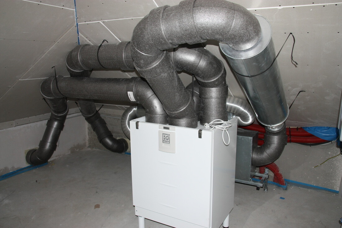 Several insulated ventilation ducts connect to a white heating/ventilation box in the basement.