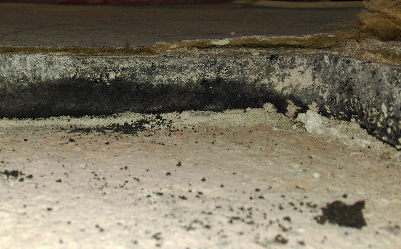 Close-up of a dirty concrete step with black deposit and dust.