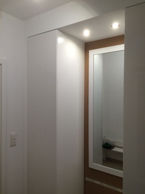White wardrobe next to brown-framed mirror in modern hallway