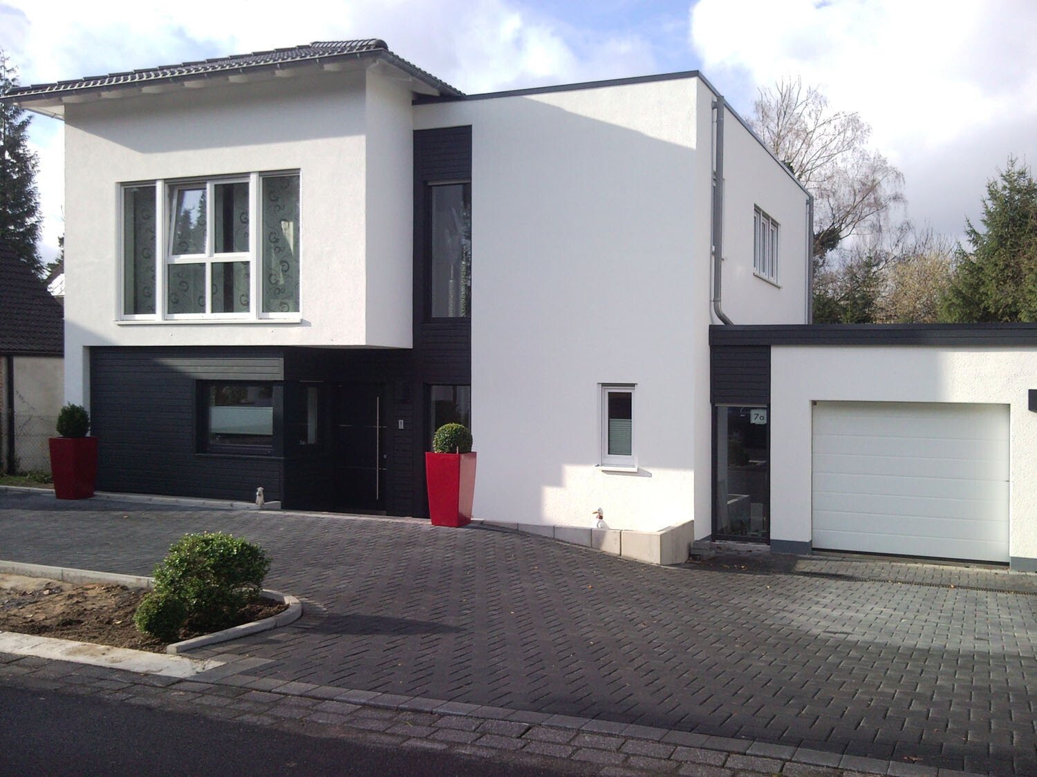 Modern two-story house with white facade, black cladding, window front, and garage.