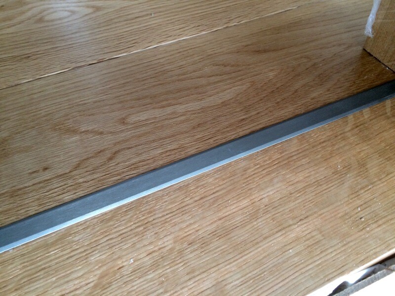 Wood parquet with a narrow metallic transition strip on the floor.