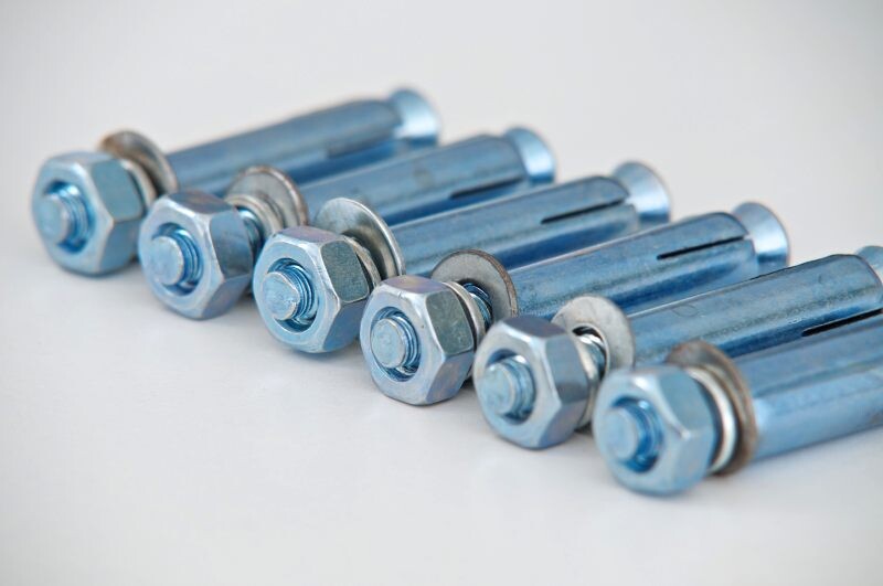 Multiple metal bolts with washers and nuts in a row