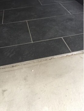 Dark rectangular floor tiles next to concrete step in entrance area