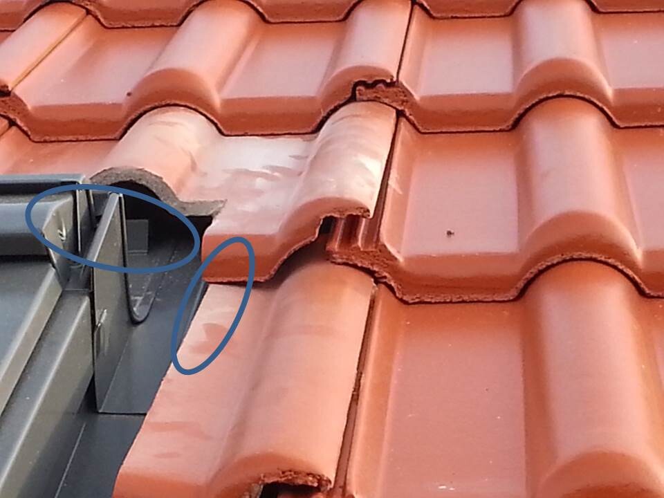 Close-up of red roof tile edge with metal flashing at the roof edge and joints