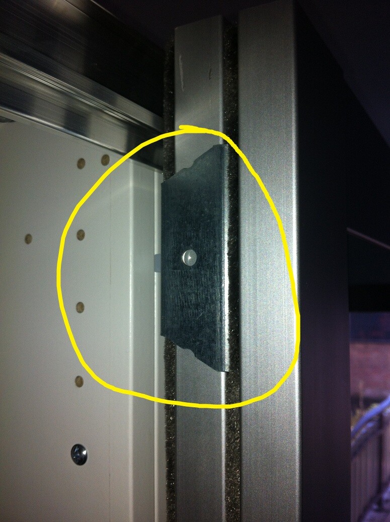 Close-up of a metallic hinge plate on the door frame with screw hole.