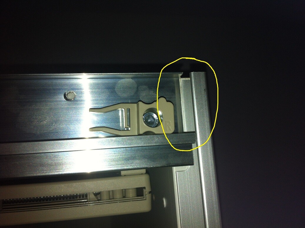 Close-up of a metal rail guide profile with beige plastic holder and screw.