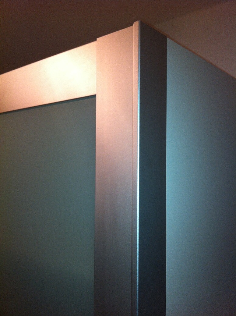 Close-up of a door frame with metal edge and blue-green door leaf.