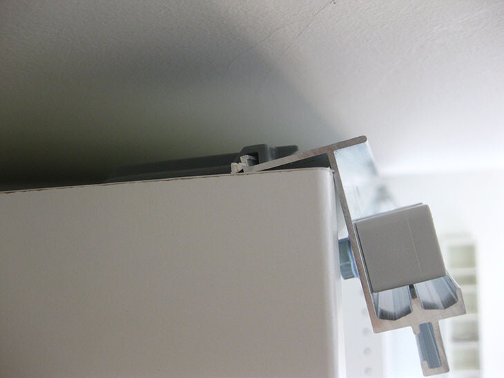 Close-up of a white kitchen cabinet fitting on the door edge, metal part visible