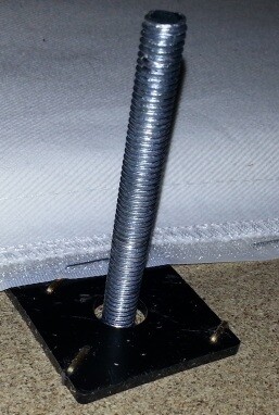 Metal threaded bolt with square base plate on light surface