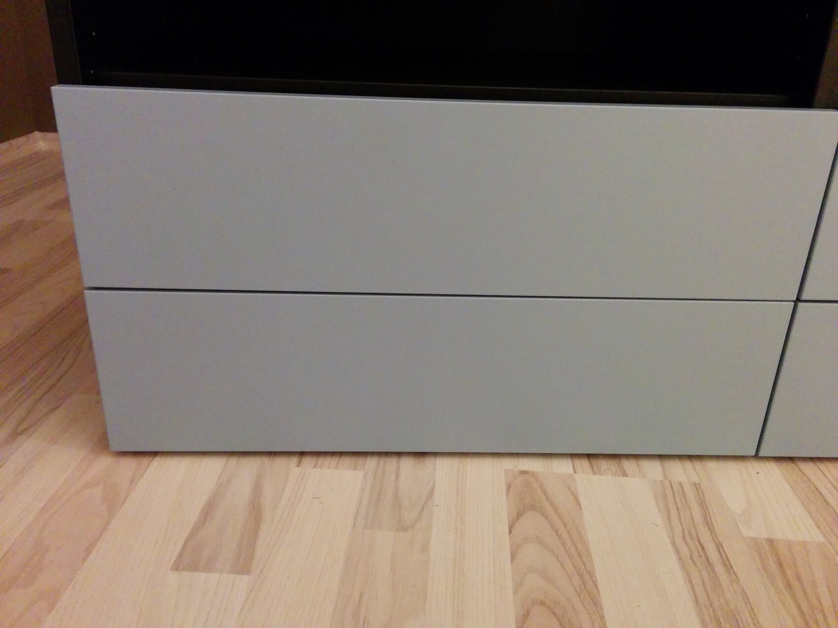 Modern gray dresser with two large drawers on light wooden flooring.