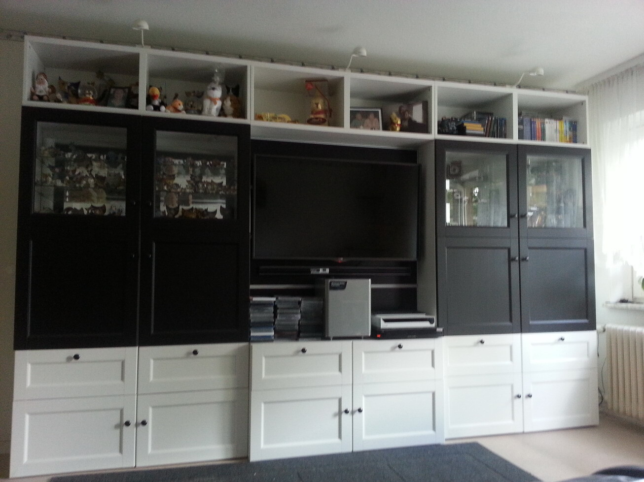 Large black-and-white wall unit with TV in the middle, glass display cabinets, and shelves.