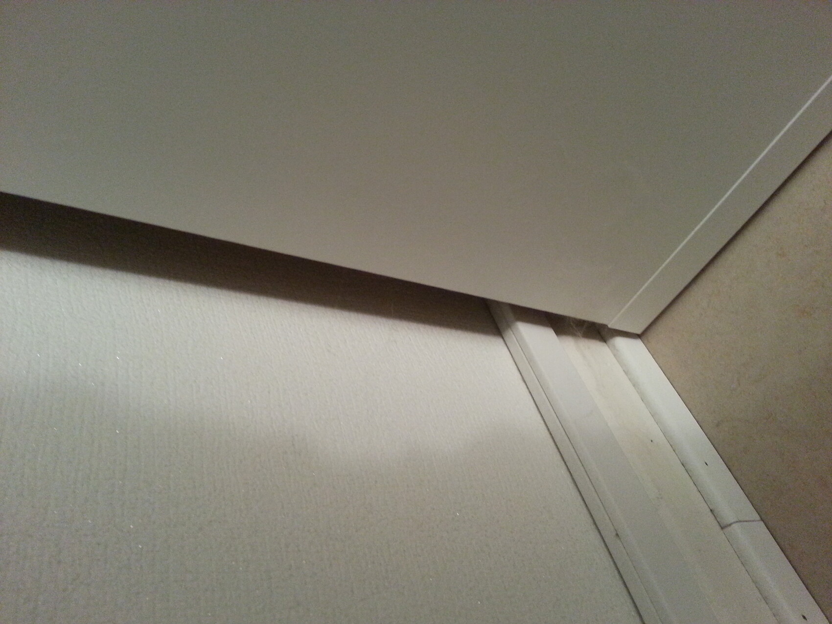 White door panel leaning at an angle against a wall in a room corner above the skirting board.