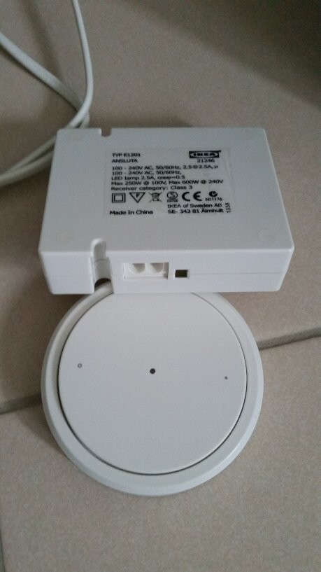 White round base with small center, on top a white rectangular power supply box with cables.