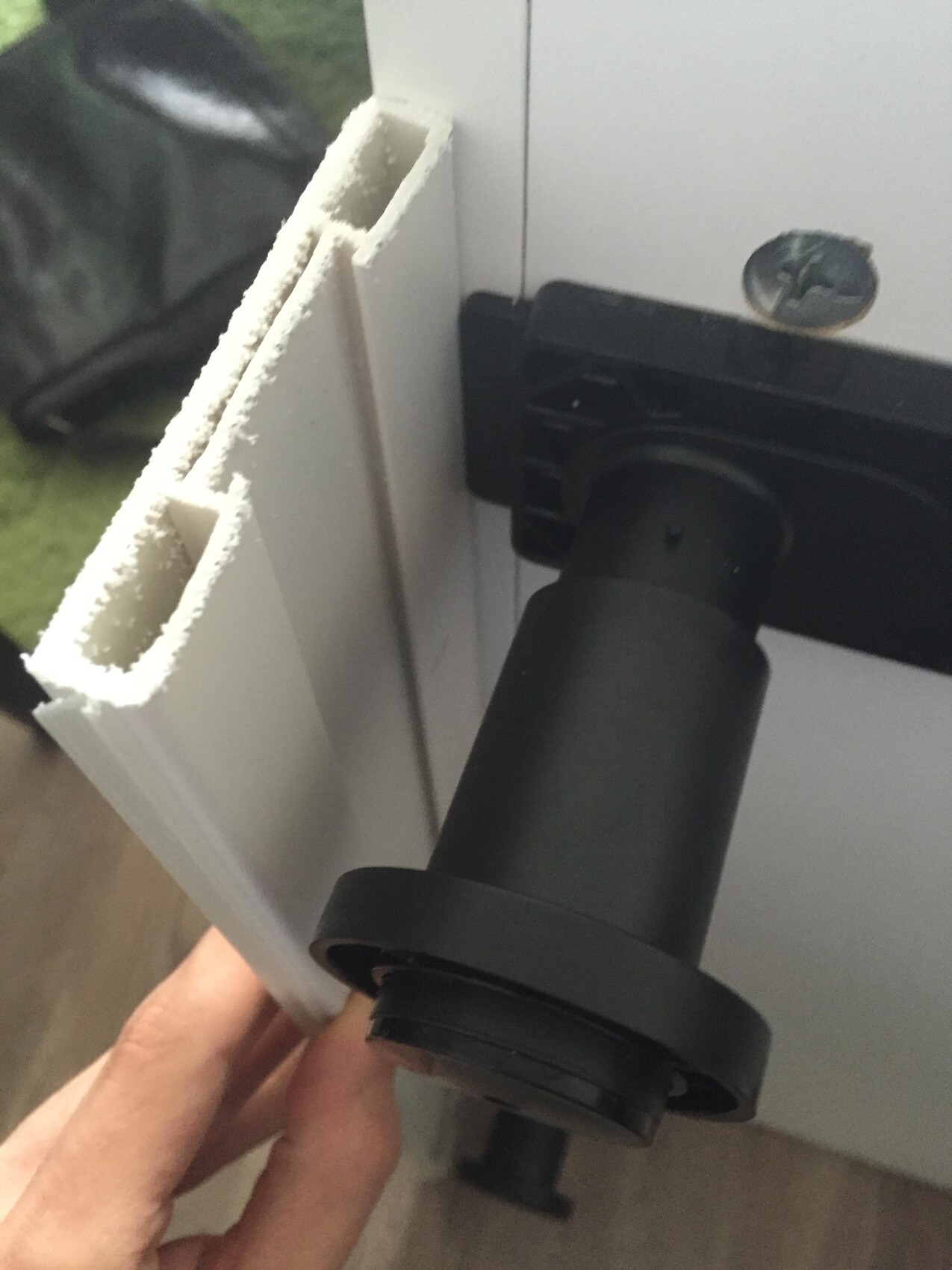 Close-up of a white plastic profile with black mounting clip; hand holding the part.