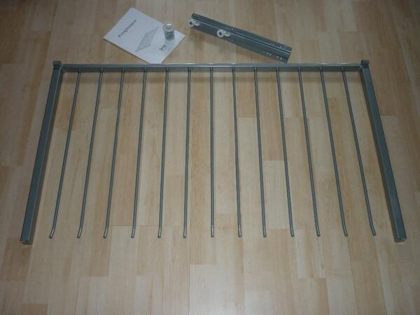 Metal frame with vertical rods on wooden floor; tools lying next to it.