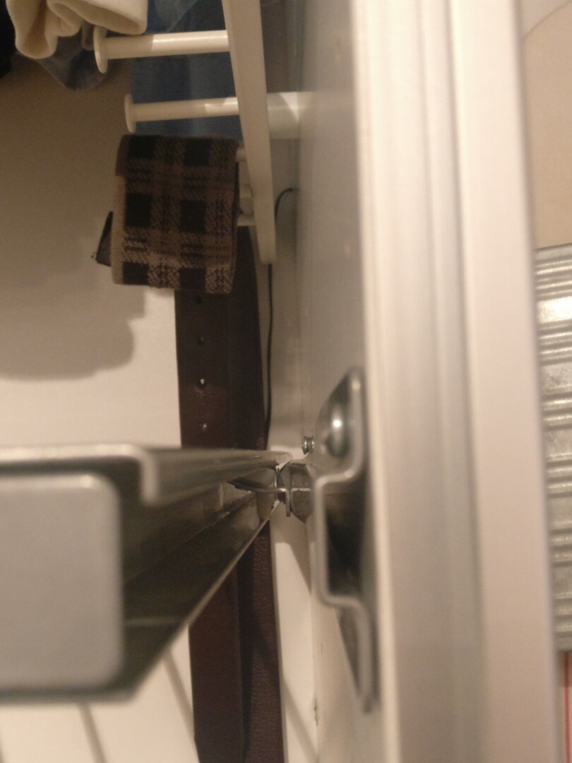 Inside view of wardrobe with metal guide rail and brown checkered cloth.