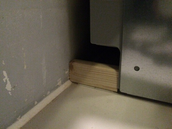Close-up of a wooden wedge under a metal appliance in the kitchen area