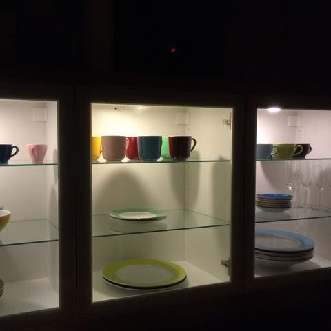 Vitrine mit farbigem Geschirr in beleuchteter Kueche