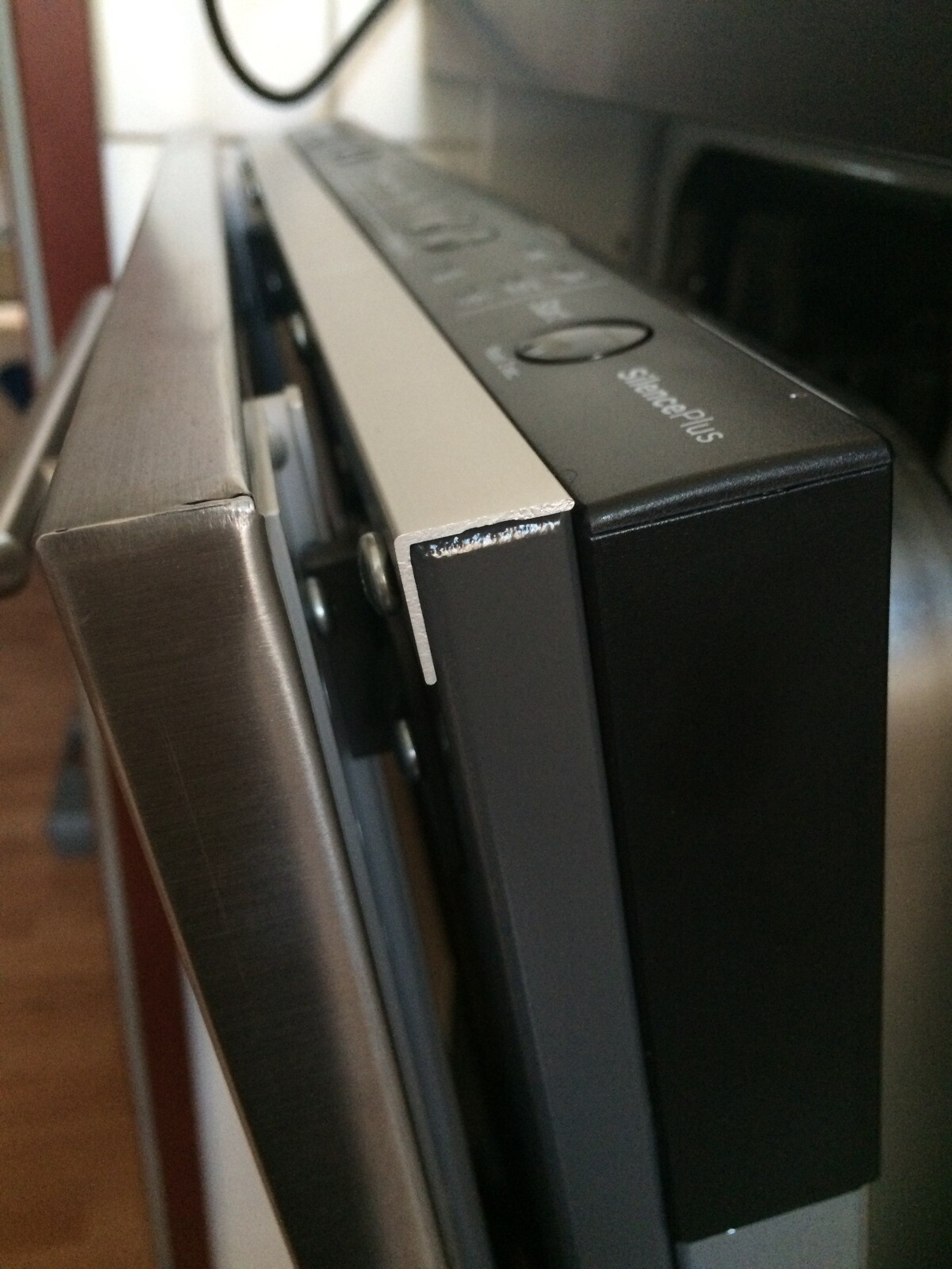 Close-up of a kitchen appliance: black casing next to a silver frame, corner slightly worn.