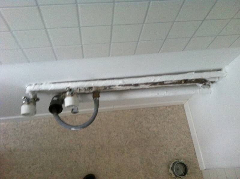 Bathroom door frame with damaged piping and wall damage