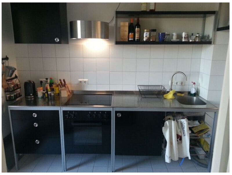 Compact kitchen with ceramic cooktop, oven, sink, dish basket and black base cabinets.